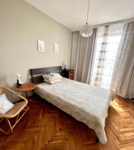 a bedroom with a bed and a table and a window at La Gare Apartment in Varna City