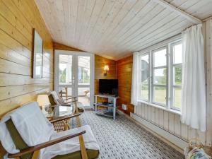 un soggiorno con sedie, TV e finestre di Holiday Home Githa - 100m to the inlet in The Liim Fiord by Interhome a Løgstør