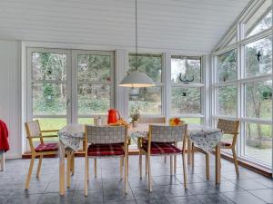 een eetkamer met een tafel, stoelen en ramen bij Holiday Home Marlien - 1km to the inlet in The Liim Fiord by Interhome in Løgsted