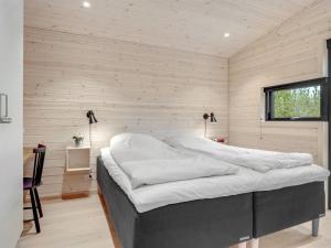 1 dormitorio con 1 cama en una habitación con paredes de madera en Holiday Home Gunnor - 1-3km from the sea in NW Jutland by Interhome en Fjerritslev