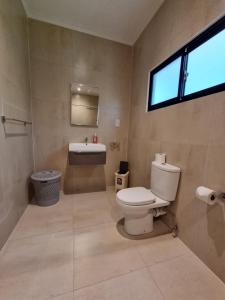 ein Bad mit einem WC, einem Waschbecken und einem Fenster in der Unterkunft Villa Laure in Grand'Anse Praslin