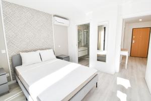 科英布拉的住宿－Brasil Residences，白色的卧室设有一张大床和一间浴室。