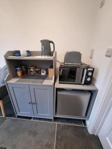 a small kitchen with a microwave and a stove at The Den - A modern, quirky room, new for 2023. in Braunton