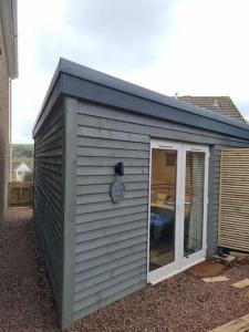 a gray shed with a door and a window at The Den - A modern, quirky room, new for 2023. in Braunton