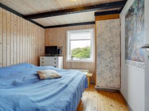 sypialnia z niebieskim łóżkiem i oknem w obiekcie Holiday Home Stella - 700m from the sea in NW Jutland by Interhome w mieście Hjørring