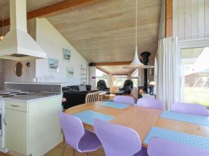 een keuken en eetkamer met een houten tafel en paarse stoelen bij Holiday Home Fanni - 300m from the sea in NW Jutland by Interhome in Hjørring