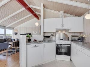 a kitchen with white cabinets and a dining room at Holiday Home Randulf - 450m from the sea in NW Jutland by Interhome in Hjørring