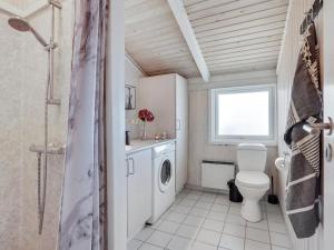 a bathroom with a toilet and a washing machine at Holiday Home Randulf - 450m from the sea in NW Jutland by Interhome in Hjørring
