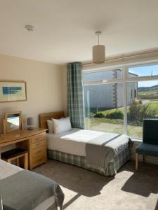 1 dormitorio con cama, escritorio y ventana en Martyrs Bay Rooms, en Iona