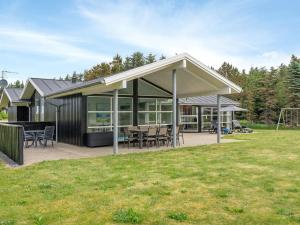 una casa con un gran techo con mesas y sillas en Holiday Home Aiyana - 530m from the sea in NW Jutland by Interhome, en Hjørring
