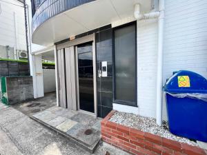una puerta de entrada de un edificio con un cubo de basura en Fieldnever Apartment STAY - Maisonette Family room en Fukuoka
