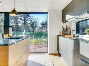une cuisine avec un évier et une grande fenêtre dans l'établissement Holiday Home Remko - 1-5km from the sea in NW Jutland by Interhome, à Hjørring