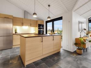 uma cozinha com armários de madeira e uma grande janela em Holiday Home Sasja - 1-5km from the sea in NW Jutland by Interhome em Hjørring