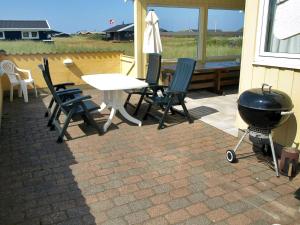 a grill on a patio with chairs and a table at Holiday Home Thorir - 300m from the sea in NW Jutland by Interhome in Hirtshals