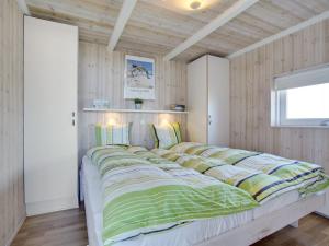uma cama grande num quarto com paredes de madeira em Holiday Home Konsta - all inclusive - 200m from the sea by Interhome em Hjørring