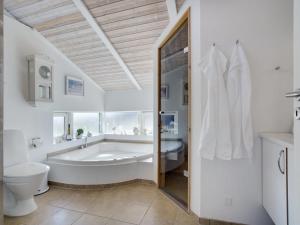 uma ampla casa de banho branca com uma banheira e um WC. em Holiday Home Konsta - all inclusive - 200m from the sea by Interhome em Hjørring