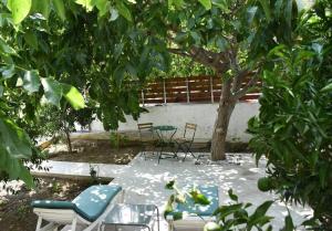 a patio with chairs and a table and a tree at Pirgos Colorful Studio Sleeps 2 Parking WiFi Ac in Rotásion