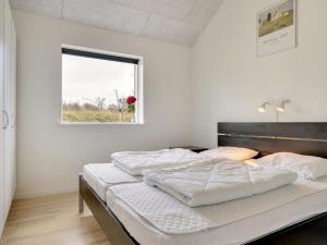 a white bedroom with a large bed with a window at Holiday Home Swarthofthi - all inclusive - 1-5km from the sea by Interhome in Hjørring