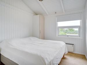 una camera da letto bianca con un letto e una finestra di Holiday Home Amalie - 650m from the sea by Interhome a Hjørring