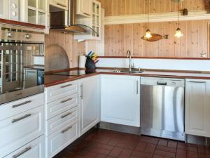 a kitchen with white cabinets and a stainless steel dishwasher at Holiday Home Marlena - 150m from the sea in NE Jutland by Interhome in Frederikshavn