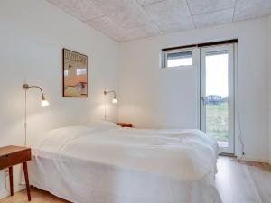 biała sypialnia z łóżkiem i oknem w obiekcie Holiday Home Anabel - 500m from the sea in NE Jutland by Interhome w mieście Frederikshavn