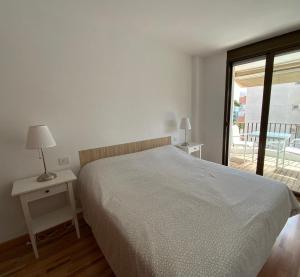 Habitación blanca con cama y balcón. en LETS HOLIDAYS Quiet apartment with pool in tossa en Tossa de Mar