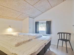 - une chambre avec un grand lit et une chaise dans l'établissement Holiday Home Riika - 425m from the sea in NW Jutland by Interhome, à Hirtshals