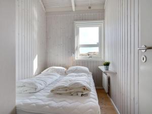 - une chambre avec un lit doté de draps blancs et une fenêtre dans l'établissement Holiday Home Fransisca - 600m from the sea in NW Jutland by Interhome, à Bindslev