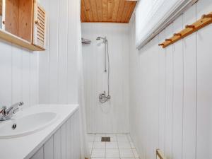 a white bathroom with a sink and a shower at Holiday Home Asmara - 200m from the sea in NE Jutland by Interhome in Læsø