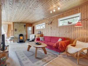 a living room with a red couch and a fireplace at Holiday Home Asmara - 200m from the sea in NE Jutland by Interhome in Læsø