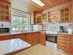 a kitchen with wooden cabinets and a large window at Holiday Home Asmara - 200m from the sea in NE Jutland by Interhome in Læsø