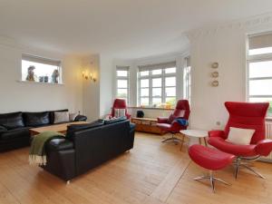 a living room with a couch and red chairs at Holiday Home Kosara - 50m from the sea in NE Jutland by Interhome in Frederikshavn
