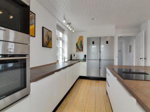 una cocina con armarios blancos y electrodomésticos de acero inoxidable en Holiday Home Kosara - 50m from the sea in NE Jutland by Interhome, en Frederikshavn