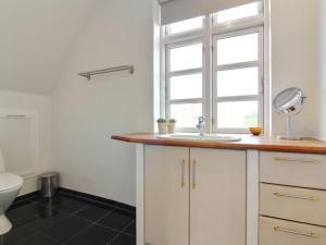 a bathroom with a sink and a window and a toilet at Holiday Home Kosara - 50m from the sea in NE Jutland by Interhome in Frederikshavn