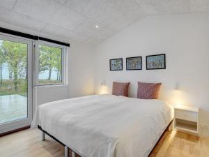 - une chambre blanche avec un grand lit et une fenêtre dans l'établissement Holiday Home Djuna - 200m from the sea in NE Jutland by Interhome, à Læsø