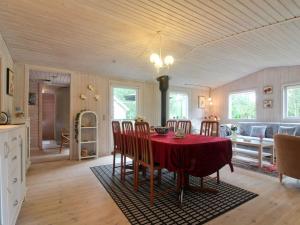 a kitchen and dining room with a red table and chairs at Holiday Home Elmer - 400m from the sea in NE Jutland by Interhome in Jerup