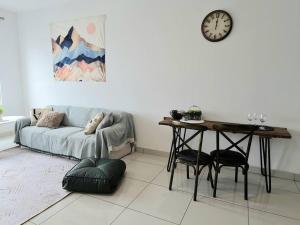 un soggiorno con divano, tavolo e orologio. di Impiria Residensi #Link Aeon Mall Klang 4BR3Bath a Klang