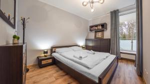 Un dormitorio con una cama grande y una ventana en Apartamenty Sun & Snow Międzyzdroje Aquamarina, en Międzyzdroje
