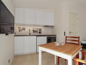 a kitchen with a wooden table and white cabinets at Apartment Alkmund - 800m from the sea in NW Jutland by Interhome in Skagen
