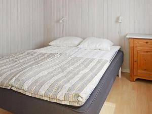 een ongeëvenaard bed in een slaapkamer met een houten kast bij Holiday Home Silje - 600m from the sea in NW Jutland by Interhome in Skagen