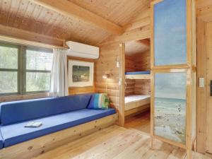 ein Zimmer mit einem blauen Sofa in einem Blockhaus in der Unterkunft Holiday Home Tumi - 700m from the sea in NE Jutland by Interhome in Læsø