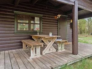 einem Picknicktisch und einer Bank auf einer Veranda einer Hütte in der Unterkunft Holiday Home Tumi - 700m from the sea in NE Jutland by Interhome in Læsø