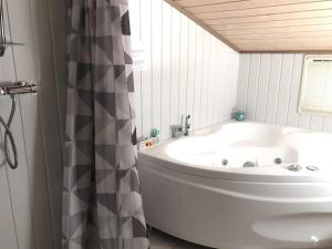 een wit bad in een badkamer met een douchegordijn bij Holiday Home Hakan - all inclusive - 4km from the sea by Interhome in Ålbæk