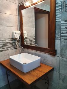een badkamer met een witte wastafel en een spiegel bij Rooms Poienita in Slănic-Moldova