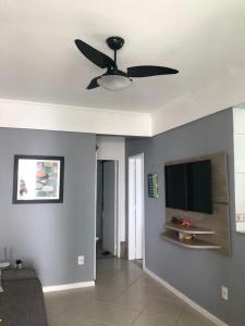 a living room with a ceiling fan and a flat screen tv at Apartamento Elizabetta 3, pé na areia in Arraial do Cabo