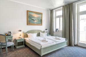 a bedroom with a bed and a desk and a window at Hotel Villa Neander in Binz