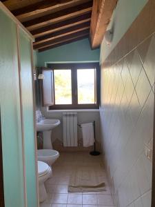 a bathroom with a sink and a toilet and a window at La Locanda Del Colle in Canalicchio