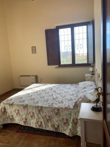 una camera da letto con un letto con copriletto floreale e 2 finestre di La Locanda Del Colle a Canalicchio