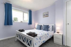 Un dormitorio con una cama con paredes azules y una ventana en Pebbles Reach, en Llanddulas