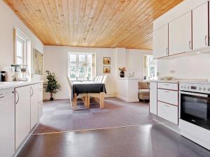 Il comprend une cuisine avec des placards blancs et un plafond en bois. dans l'établissement Holiday Home Minte - 450m from the sea in NW Jutland by Interhome, à Skagen